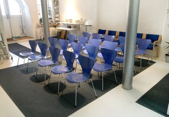 STUDIET er et unikt og inspirerende mødelokale midt på Østerbro i København. Lokalet har rustikke søjler, et spejlloft og en dejlig sydvendt gårdhave. STUDIET er på i alt 76 m2 ligger i en hyggelig gammel fabriksbygning i et stort åbent gårdmiljø.  Stedet er ideelt til møder, kurser og workshops.  Vi anbefaler 4-16 personer, men vi har dog afholt mange møder med helt op til 35 personer.  Vi har to store mødeborde med plads til 12 personer, to mindre borde med plads til 4-6 personer og 35 blå stole.  Lokalet indeholder et lille tekøkken med to effektive kaffemaskiner, en bar med køleskab og opvaskemaskine, et make-up rum med spejl og håndvask, samt et toilet.     STUDIET ligger midt i et stort og fredeligt gårdmiljø kun 200 m fra Sortedamsøen. Der er 100 meter til offentlig bustransport og ca. 1 km til Østerport og Nordhavn Station.  Der er mange parkeringspladser med timebetaling i området, og det er som regel ikke svært at finde parkering.