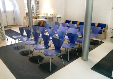 STUDIET er et unikt og inspirerende mødelokale midt på Østerbro i København. Lokalet har rustikke søjler, et spejlloft og en dejlig sydvendt gårdhave. STUDIET er på i alt 76 m2 ligger i en hyggelig gammel fabriksbygning i et stort åbent gårdmiljø.  Stedet er ideelt til møder, kurser og workshops.  Vi anbefaler 4-16 personer, men vi har dog afholt mange møder med helt op til 35 personer.  Vi har to store mødeborde med plads til 12 personer, to mindre borde med plads til 4-6 personer og 35 blå stole.  Lokalet indeholder et lille tekøkken med to effektive kaffemaskiner, en bar med køleskab og opvaskemaskine, et make-up rum med spejl og håndvask, samt et toilet.     STUDIET ligger midt i et stort og fredeligt gårdmiljø kun 200 m fra Sortedamsøen. Der er 100 meter til offentlig bustransport og ca. 1 km til Østerport og Nordhavn Station.  Der er mange parkeringspladser med timebetaling i området, og det er som regel ikke svært at finde parkering.